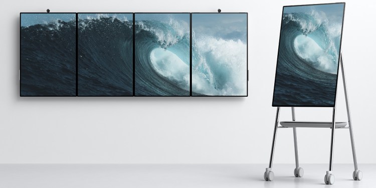 Four Microsoft's Surface Hub 2 devices on a wall and one on a stand