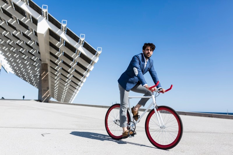 Young businessman on fixie bike outdoors.