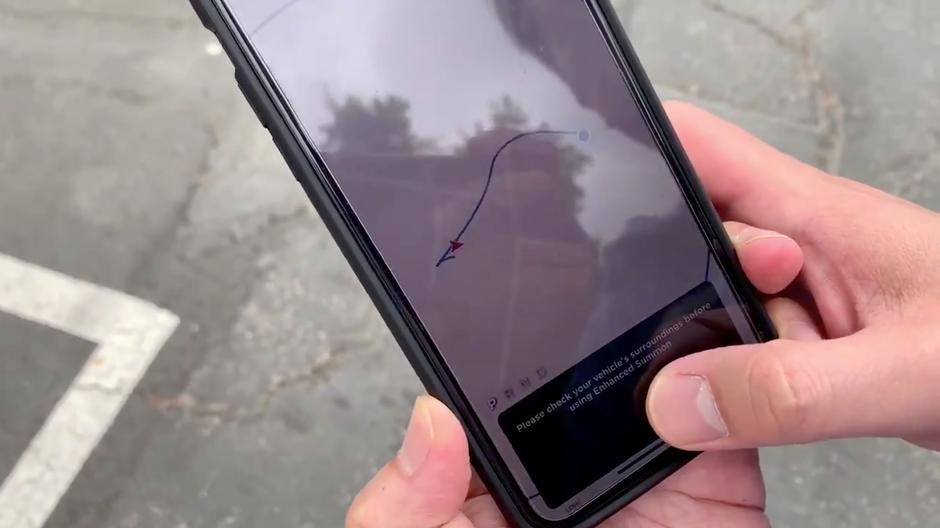 A person uses a Tesla 3 model auto parking app in Pomona, California, U.S., September 27, 2019, in this still image taken from social media video. Courtesy of