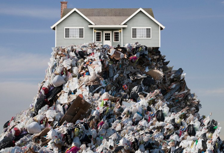 A brand new house is perched on top of a mountain of garbage